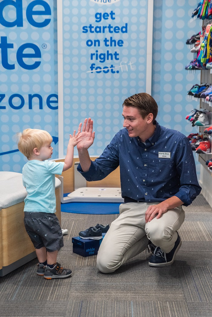 Saleperson and child high fiving at Lucky Shoes Stride Rite store